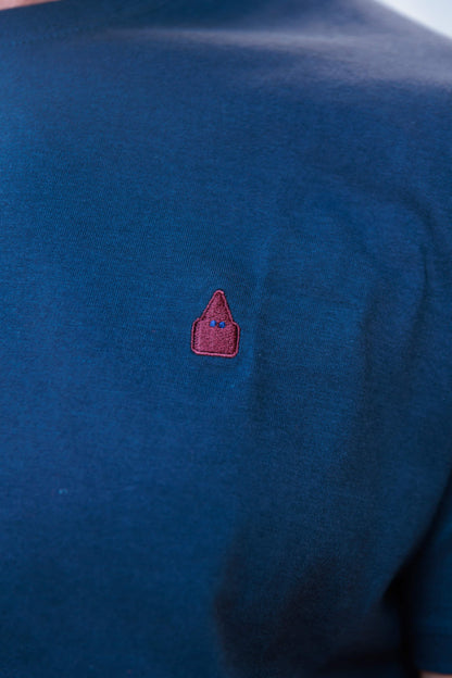 Detalle del bordado del nazareno de TRAMO en color burdeos sobre camiseta azul marino.