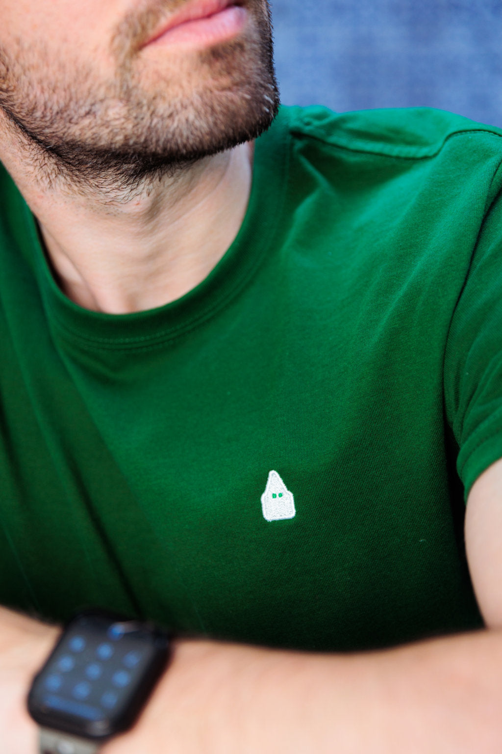 Detalle del bordado del nazareno de TRAMO en blanco sobre camiseta verde.
