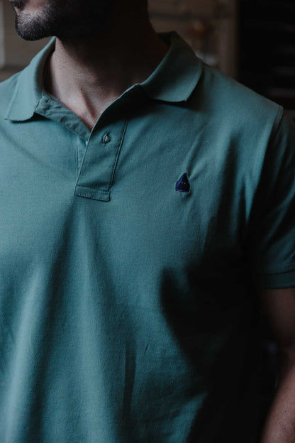 Detalle del nazareno bordado en azul marino sobre polo verde de algodón TRAMO.