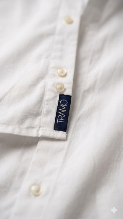 Detalle de la etiqueta TRAMO en la parte inferior de la abotonadura de una camisa blanca de algodón