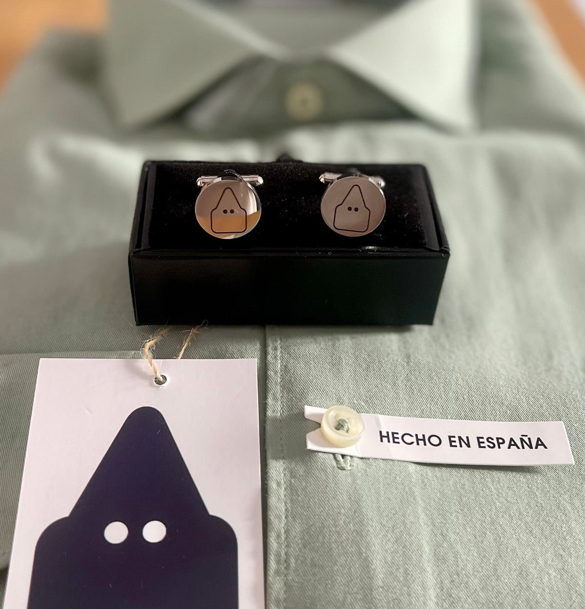 Gemelos redondos TRAMO de acero inoxidable con el nazareno grabado, presentados en su caja.