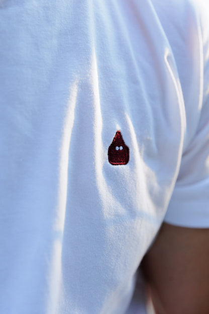 Detalle del nazareno de TRAMO bordado en burdeos sobre camiseta blanca de algodón.