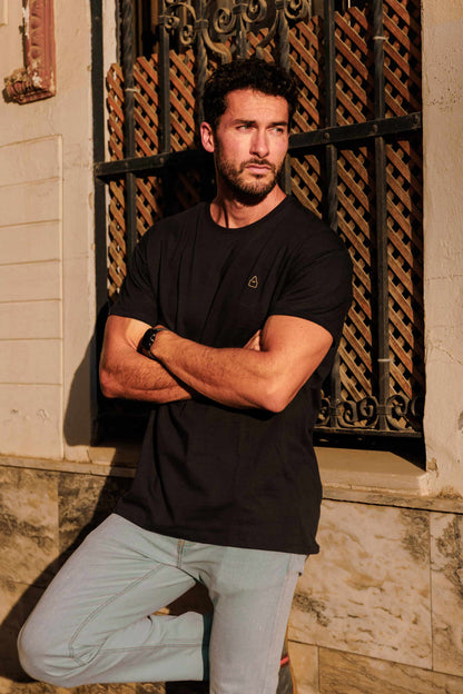 Vista de la camiseta azul marino con la silueta del nazareno de TRAMO bordada en dorado combinada con vaqueros.