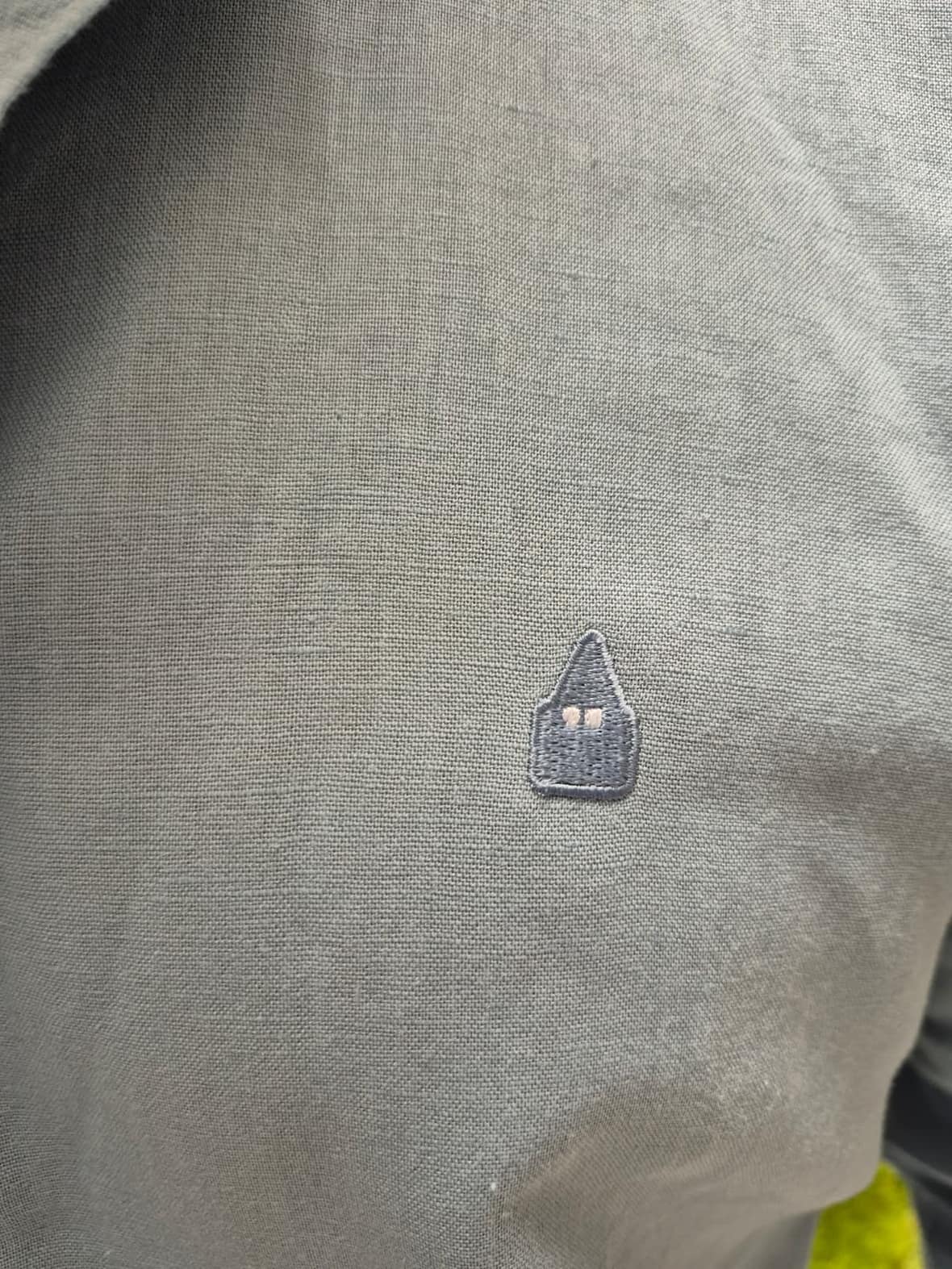detalle del logo y tejido lino camisa celeste hombre