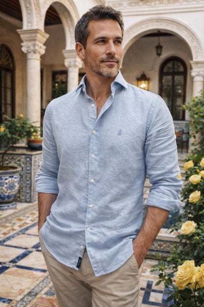 Hombre vistiendo camisa de lino celeste TRAMO y pantalón chino beige en un patio sevillano
